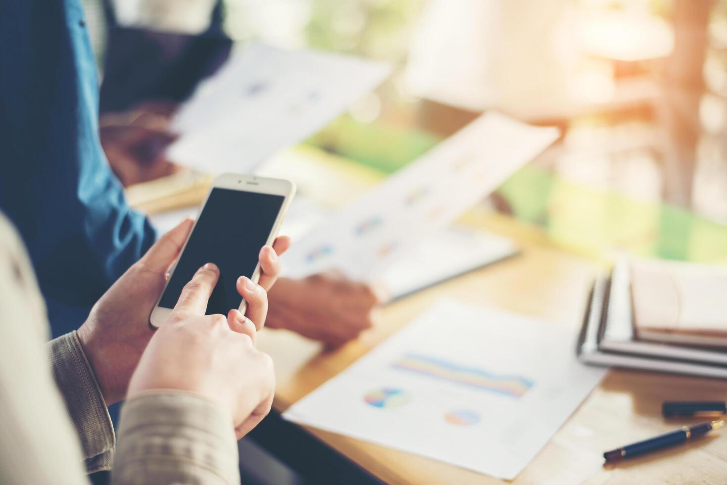 de handen van de zakenvrouw die aan slimme telefoon en bedrijfsinformatie werken foto