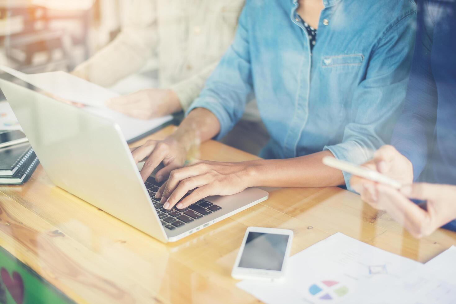 de handen van de zakenvrouw die aan slimme telefoon en laptop computer werken foto