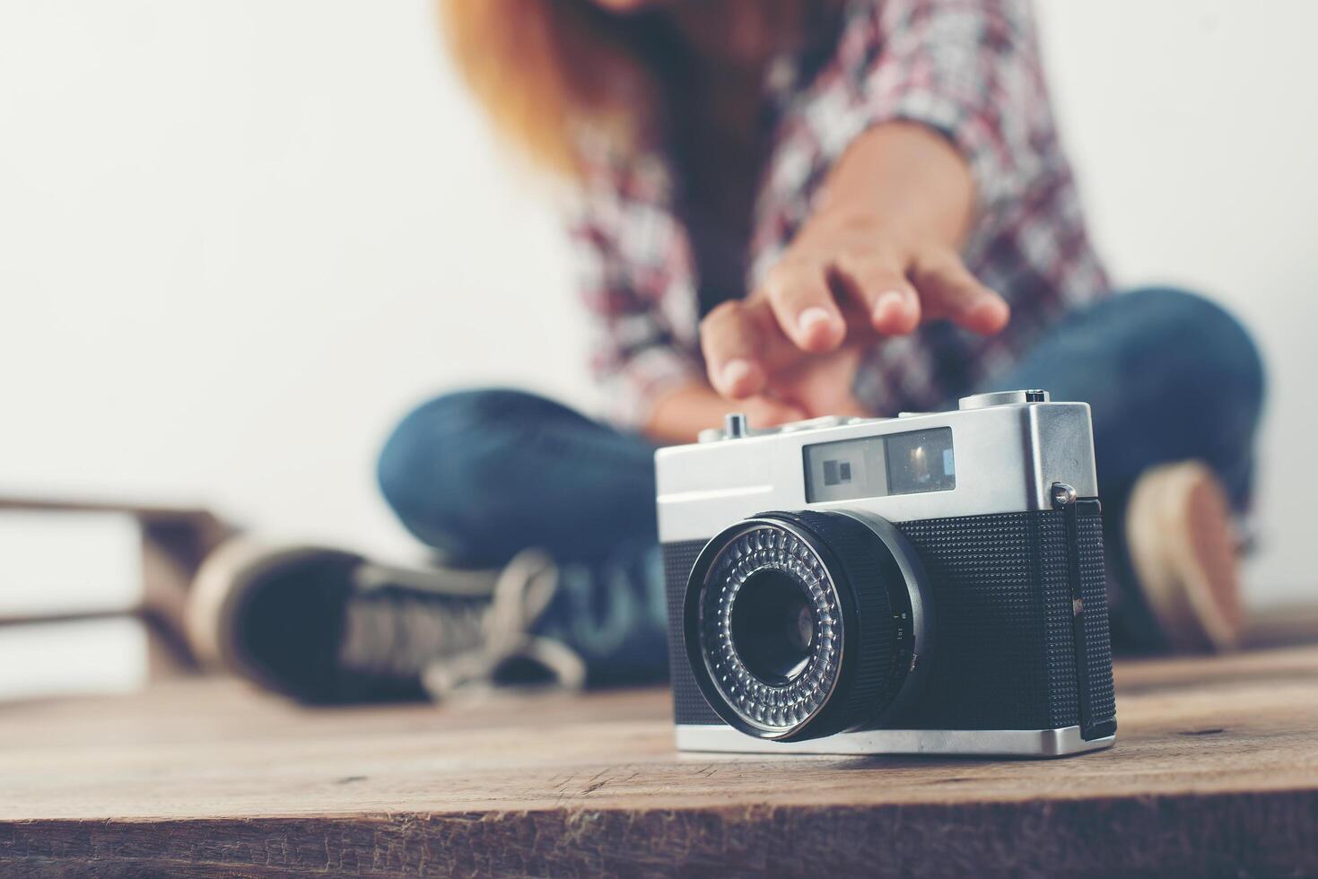 jonge hipster vrouw hand reiken voor vangst retro camera. foto