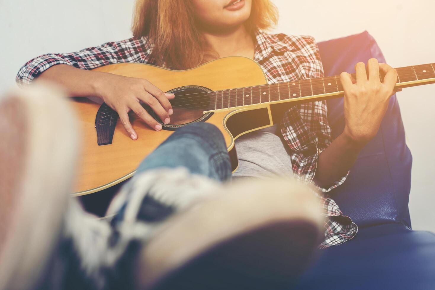 jonge hipstervrouw die een gitaar speelt. foto