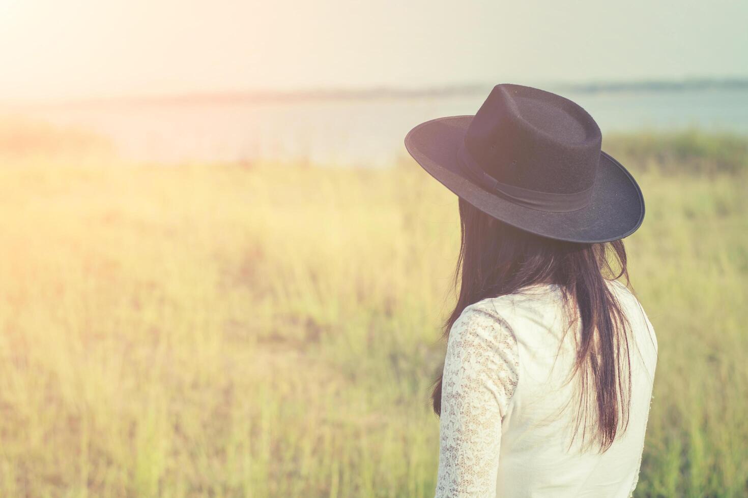 droevige vrouw die zwarte hoed draagt die zich in een weide bevindt foto