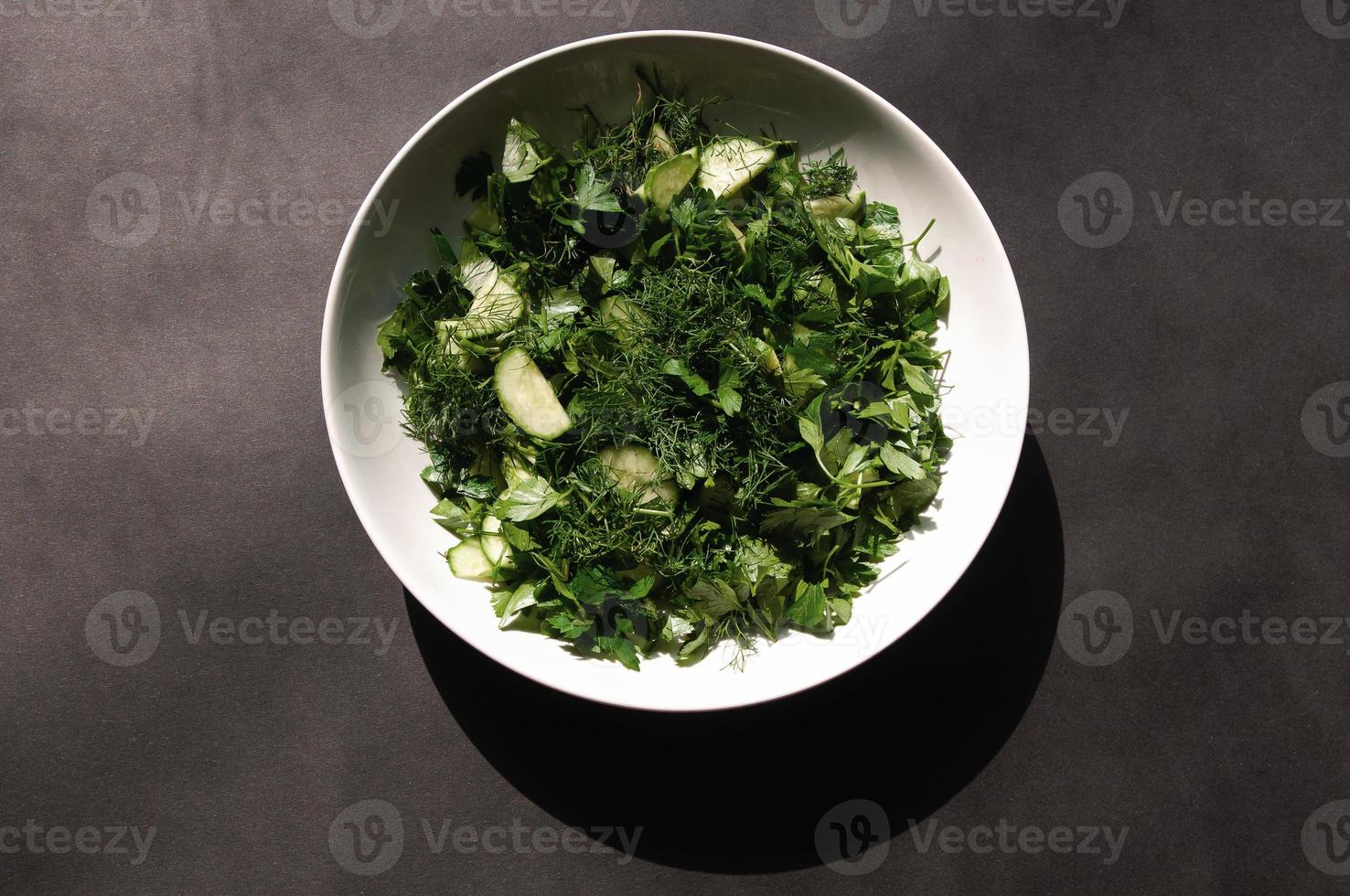 Salade met dille en peterseliekomkommers op plaat een grijze achtergrond foto