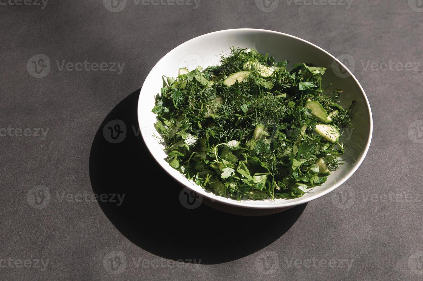 Salade met dille en peterseliekomkommers op plaat een grijze achtergrond foto