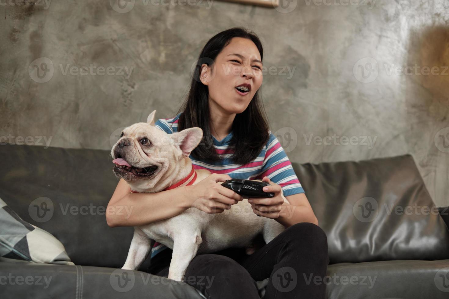 jonge vrouw speelt videogameconsole met haar schattige hond. foto