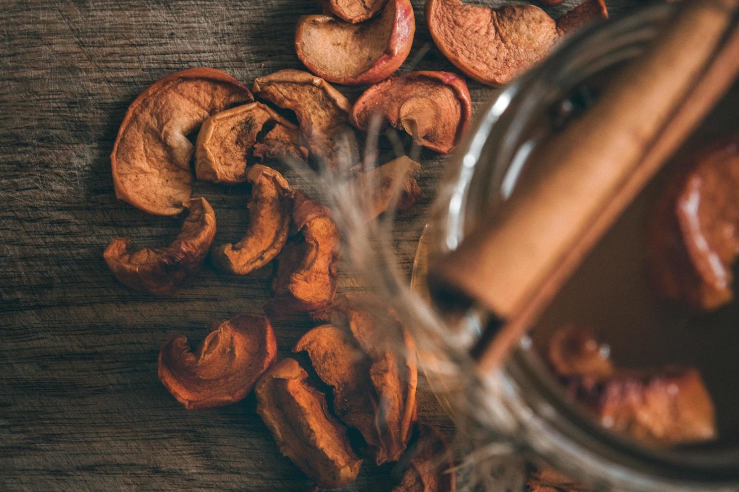 gedroogde appelschijfjes met compote in een glazen pot op een houten ondergrond foto