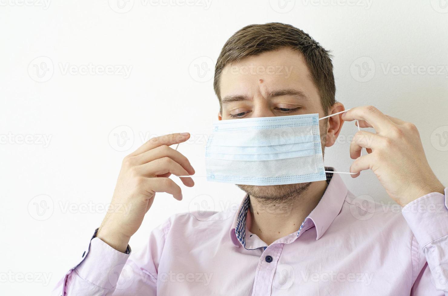 een man in een shirt zet een masker op. virus bescherming. foto