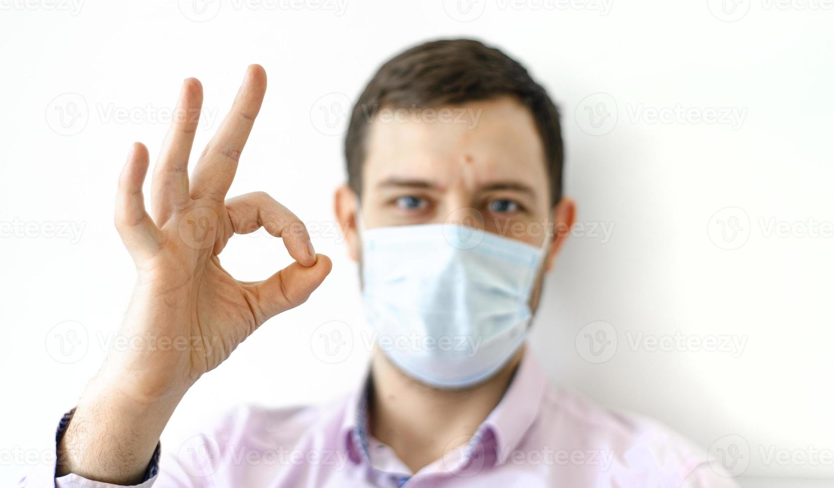 een man in een shirt met een beschermend masker. toont ok teken. foto