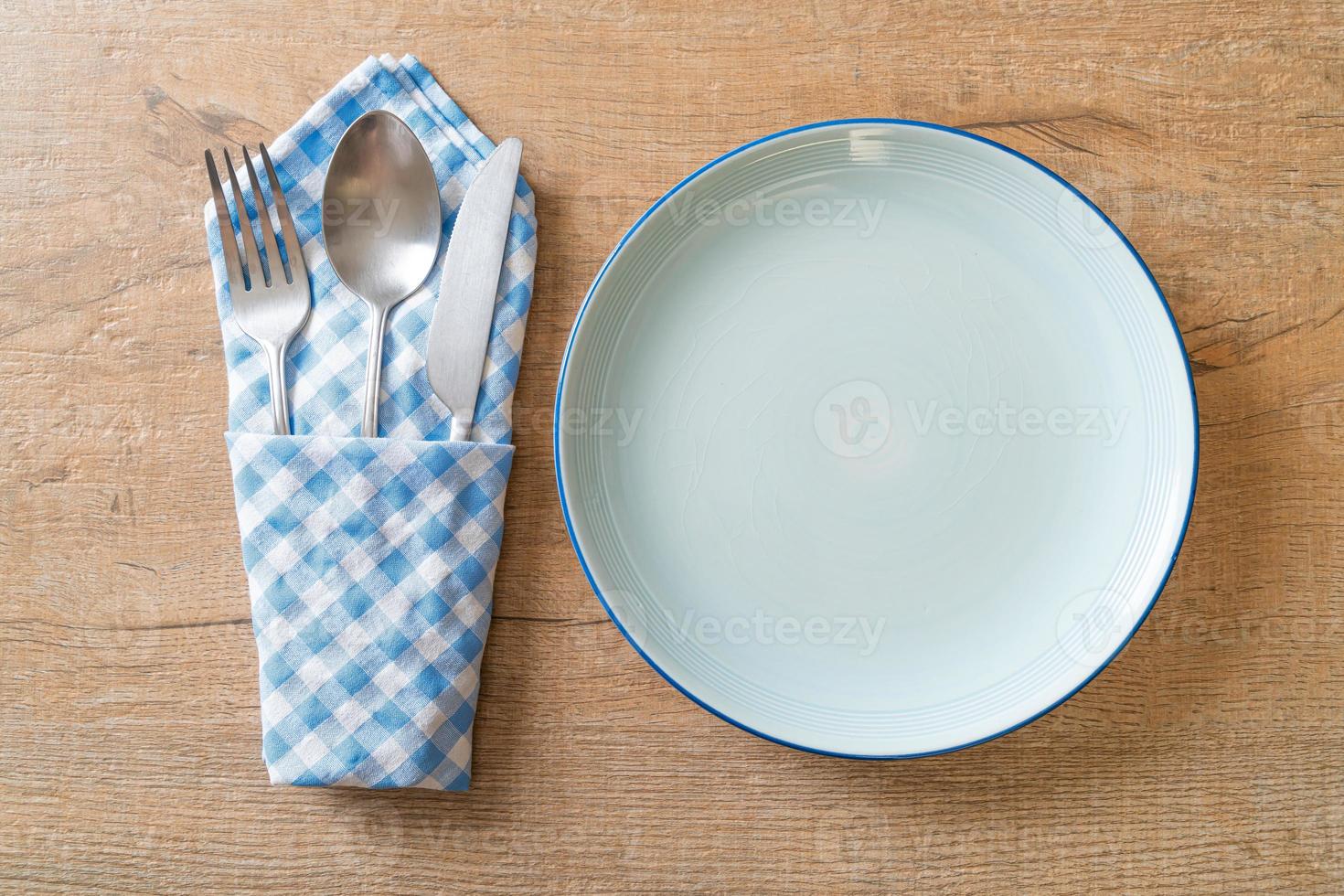 lege plaat of schotel met mes, vork en lepel op houten tegelachtergrond foto