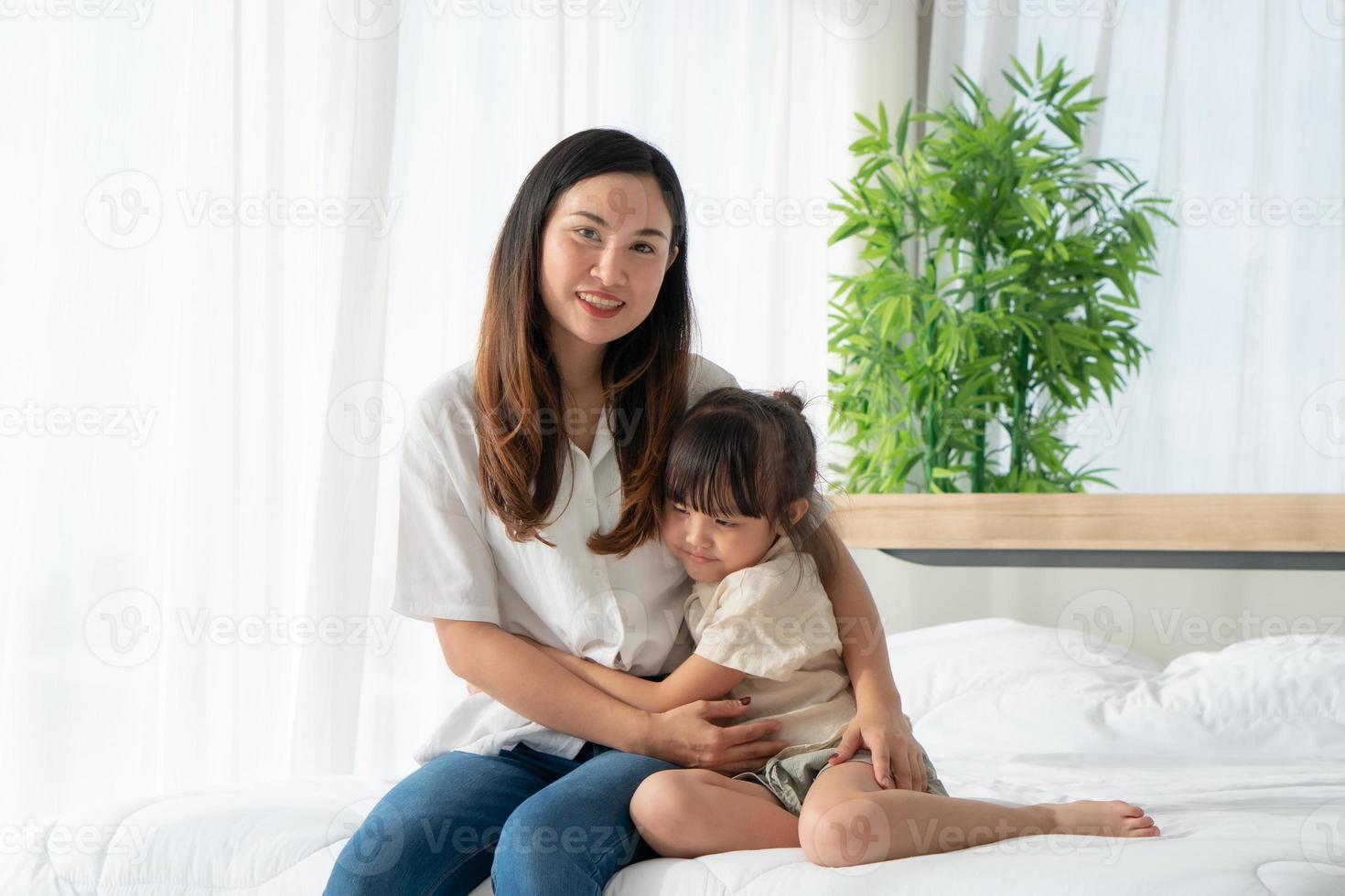 Aziatische moeder knuffelt kind in slaapkamer foto