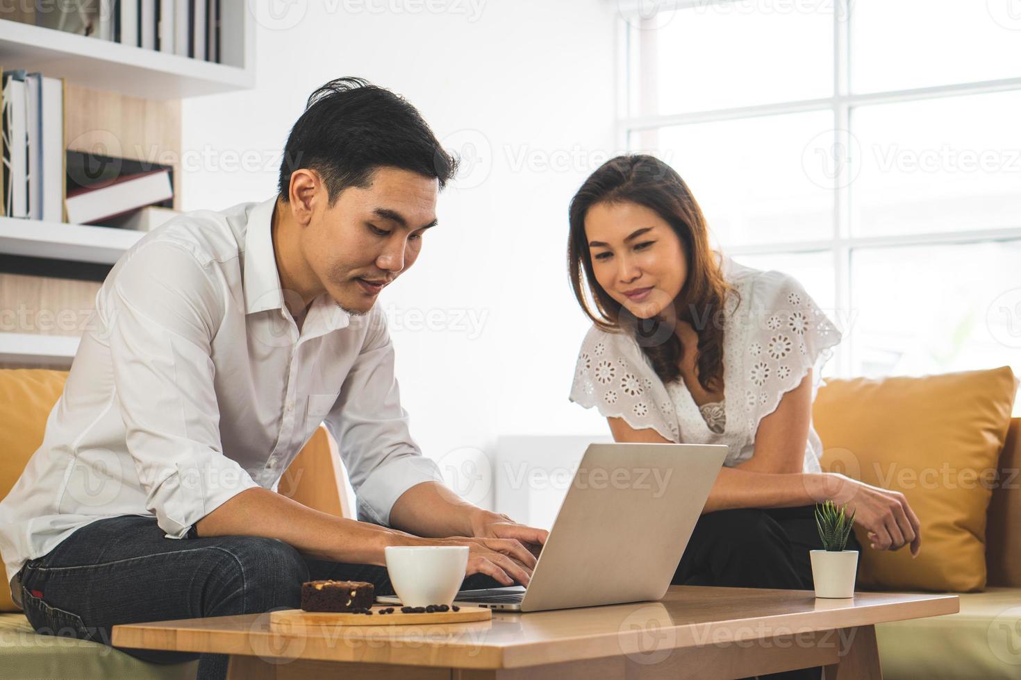 jonge aziatische man die computer gebruikt om met zijn collega in het café te werken foto