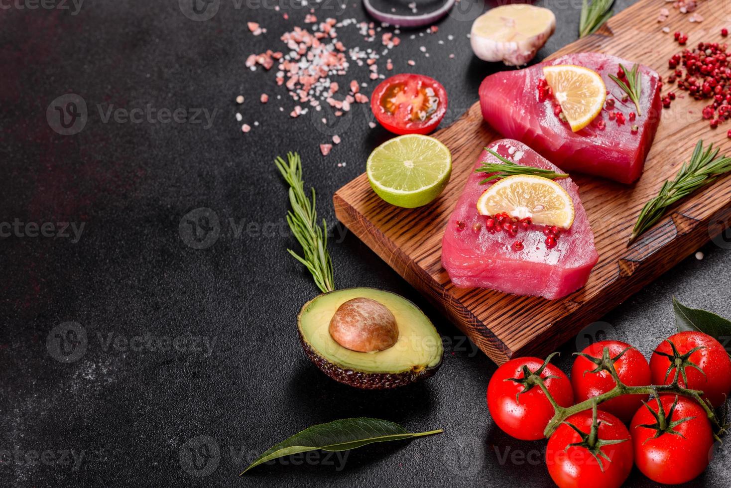 verse tonijnfilet steaks met specerijen en kruiden op een zwarte achtergrond foto