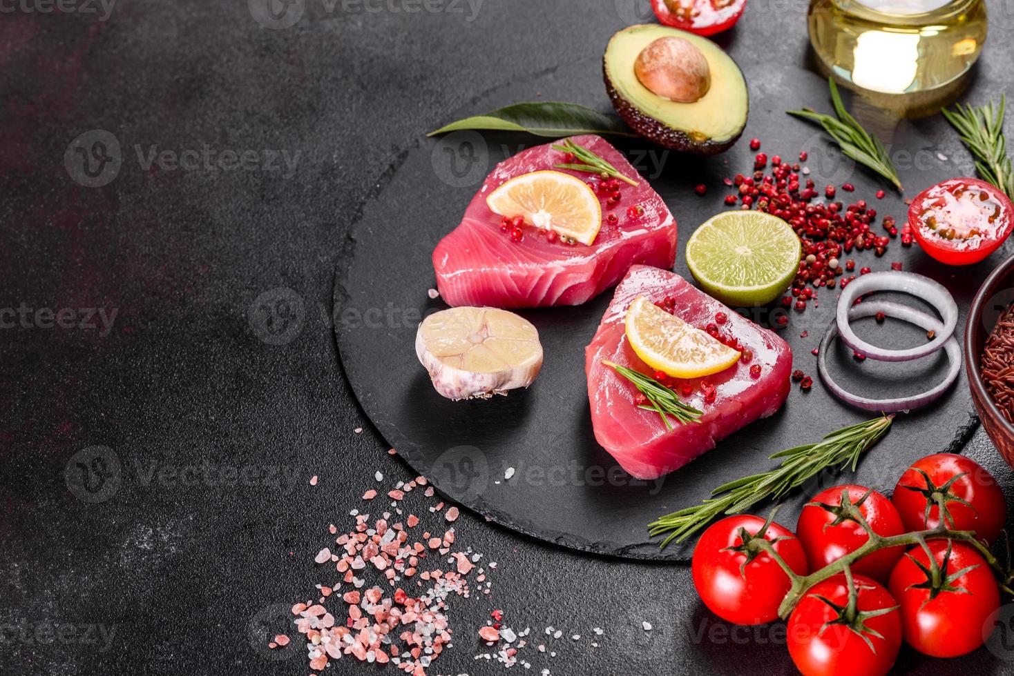 verse tonijnfilet steaks met specerijen en kruiden op een zwarte achtergrond foto