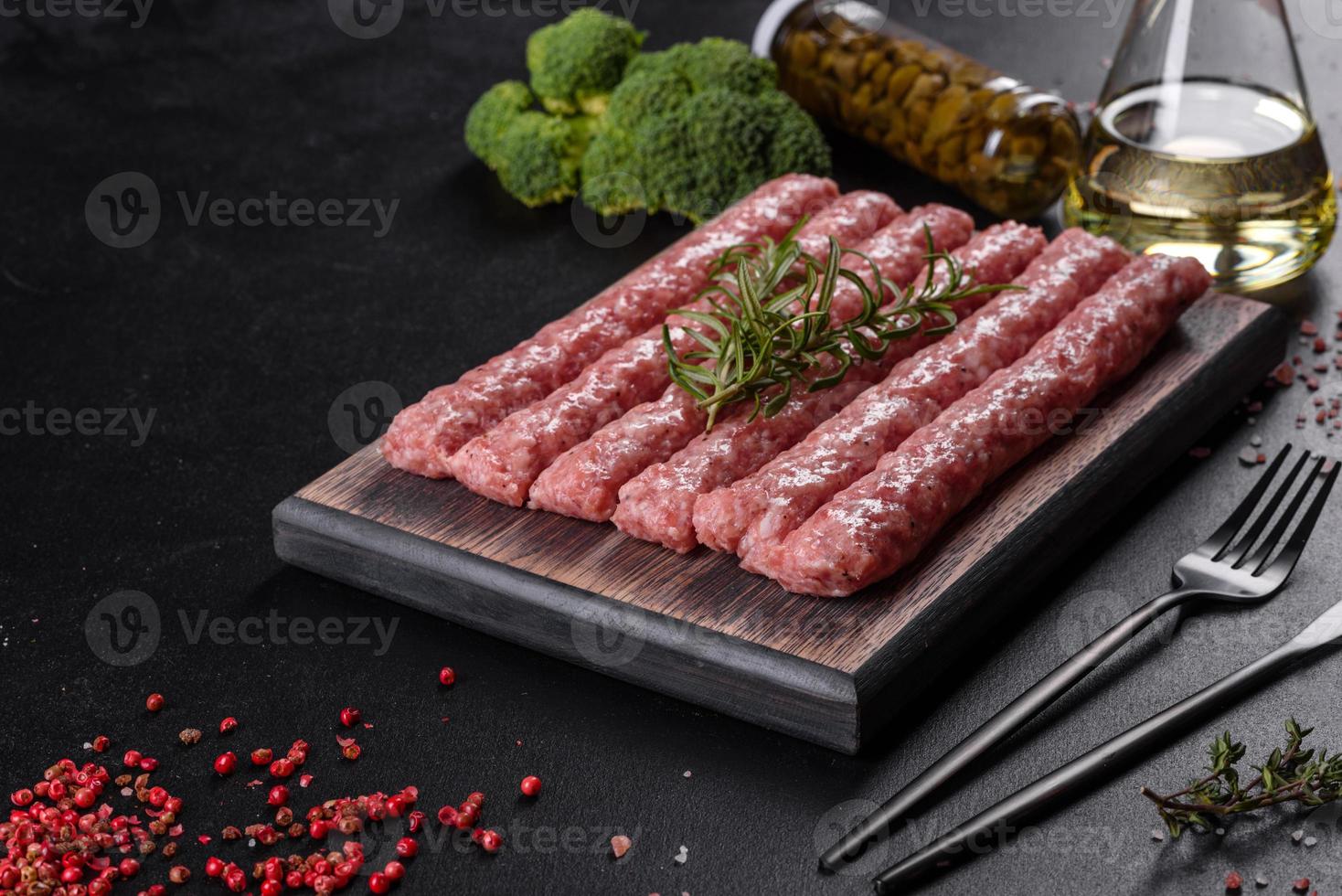 verse rauwe varkensworstjes met kruiden op een houten snijplank foto