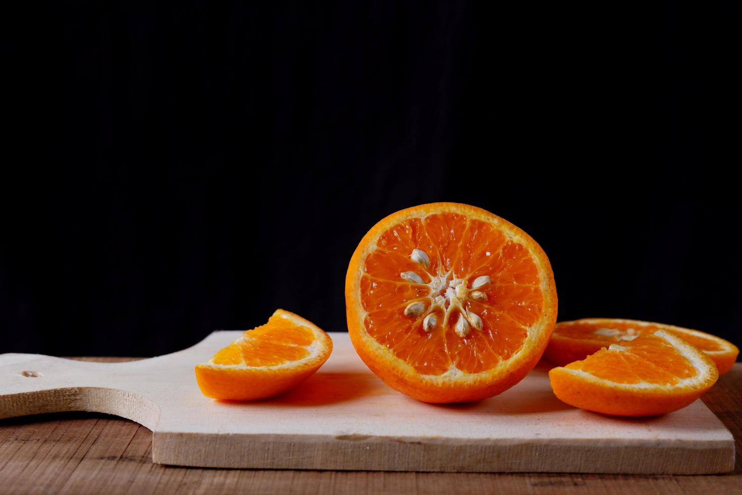 sinaasappelschijfjes op houten snijplank op zwarte achtergrond foto