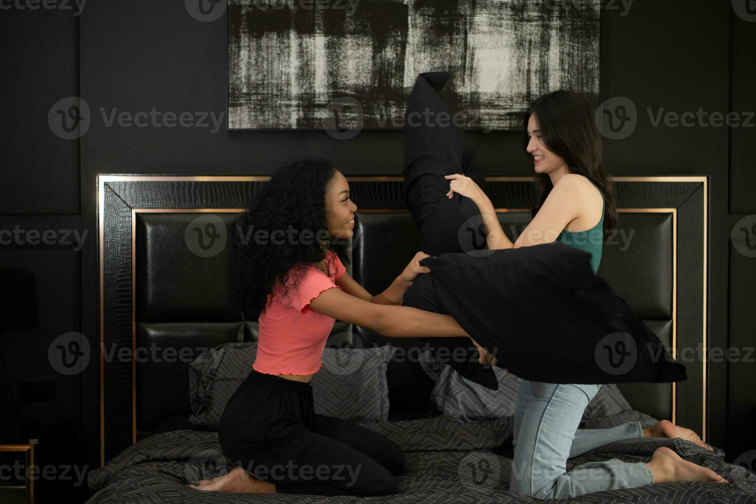 twee jong Dames Speel met kussens Aan de bed in de slaapkamer Bij huis. vriendschap en levensstijl concept. foto