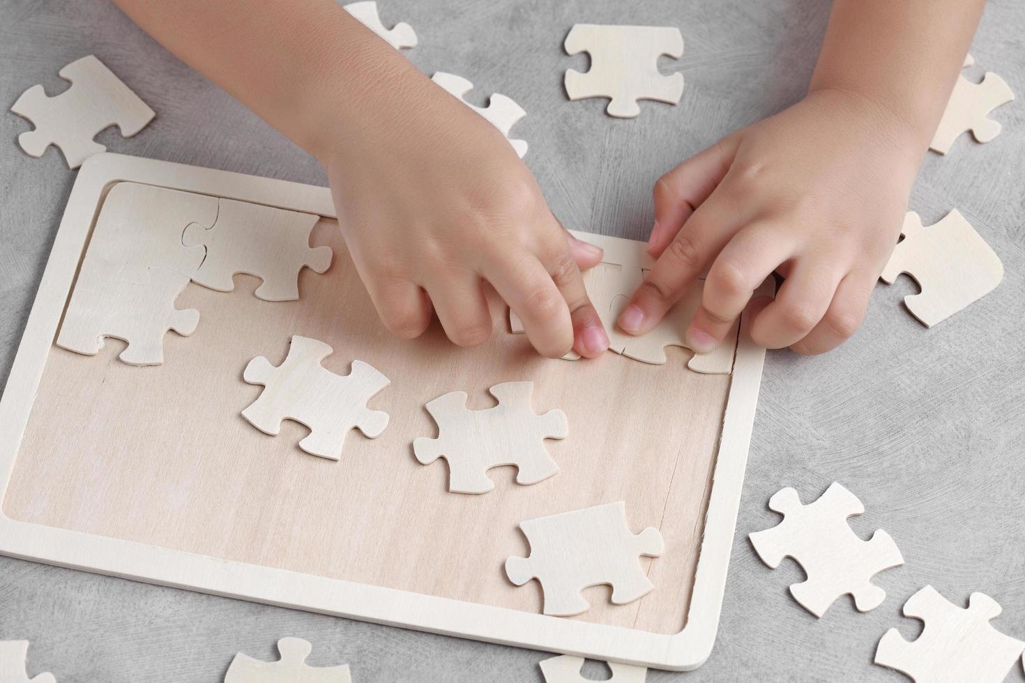 Aziatische kleine jongen die houten puzzel speelt foto