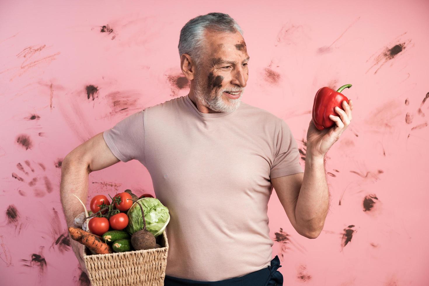 aantrekkelijke, oudere man houdt een mand met groenten vast foto