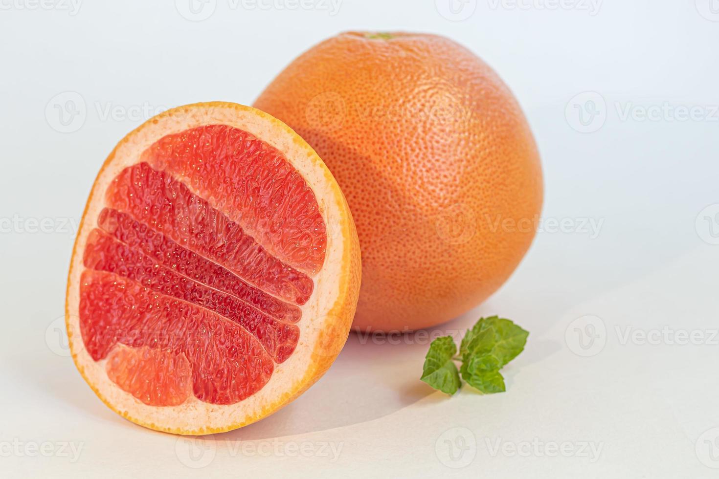 grapefruit op een witte plaat met een takje munt. isoleren. foto