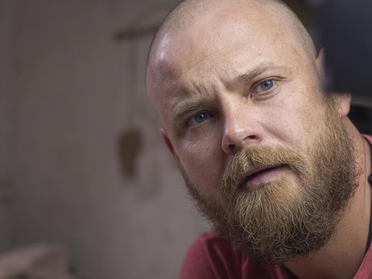 portret van een kale man met een baard met mooie blauwe ogen foto