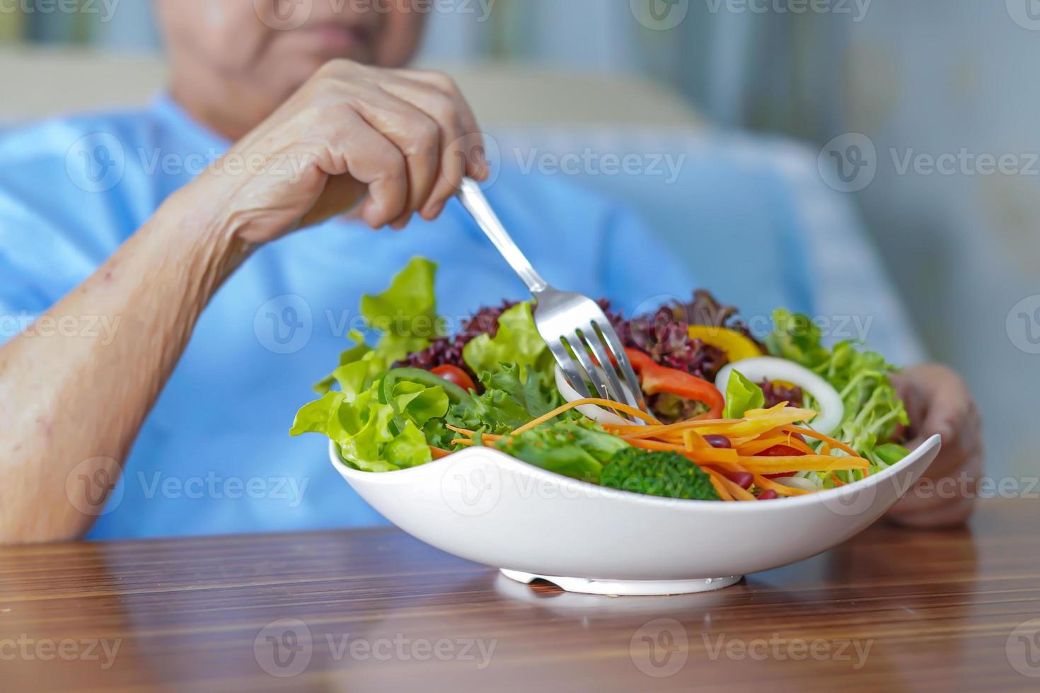 Aziatische hogere vrouwenpatiënt die ontbijt eet in het ziekenhuis foto