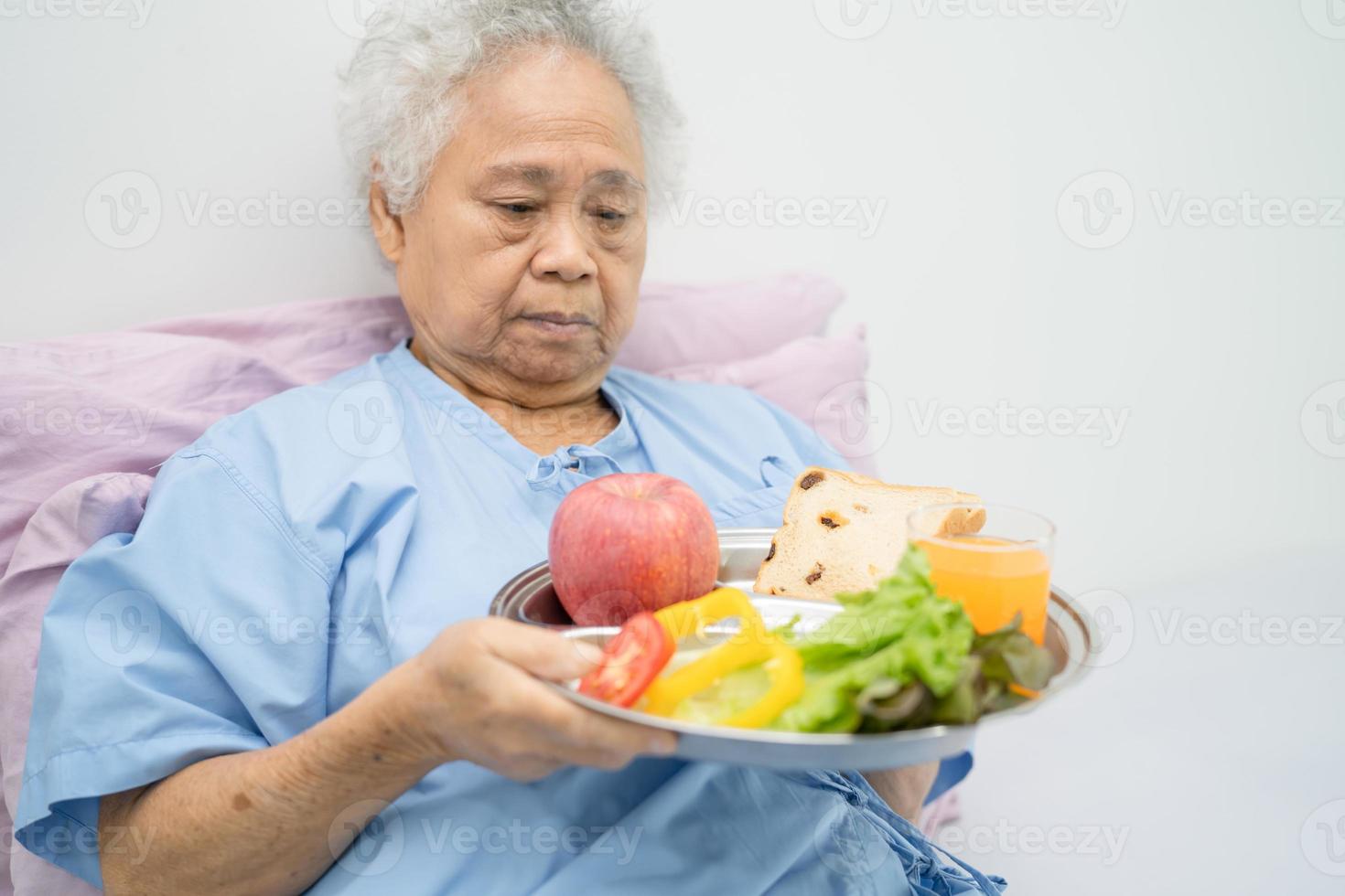 Aziatische senior vrouw patiënt eten ontbijt plantaardig voedsel foto