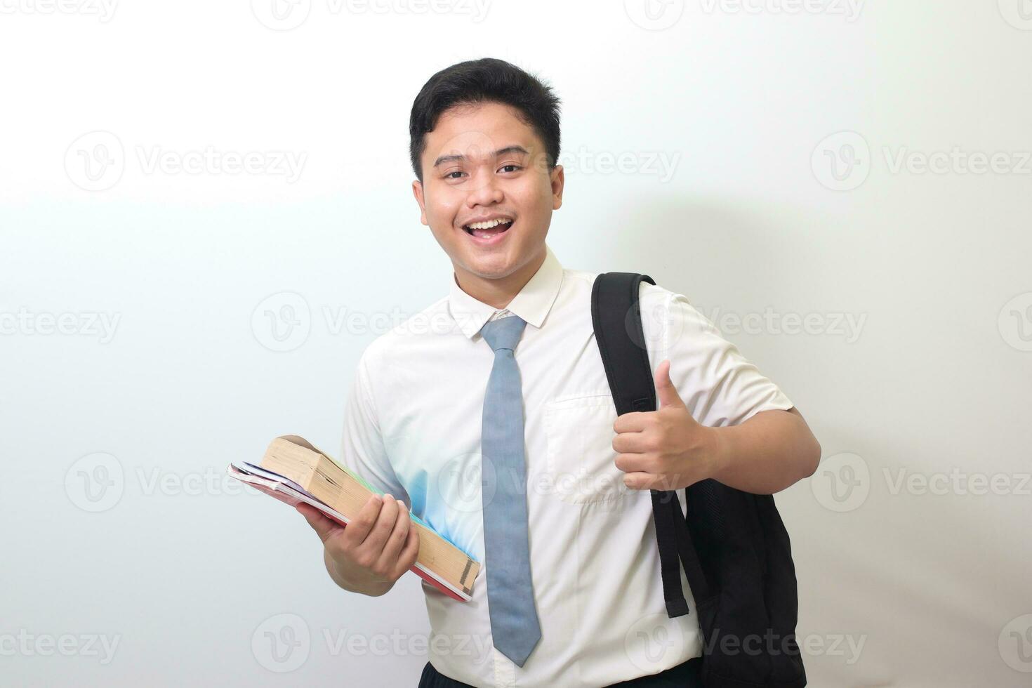 Indonesisch senior hoog school- leerling vervelend wit overhemd uniform met grijs stropdas tonen mooi zo baan hand- gebaar, duim omhoog vinger. geïsoleerd beeld Aan wit achtergrond foto