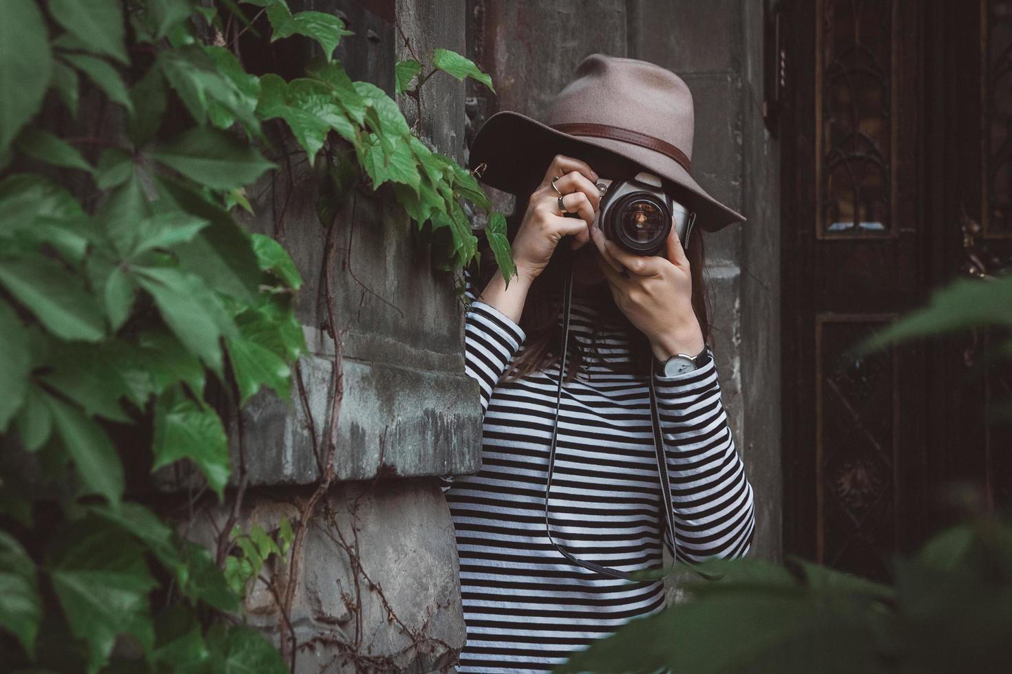 mooie vrouw met hoed maakt foto met ouderwetse camera