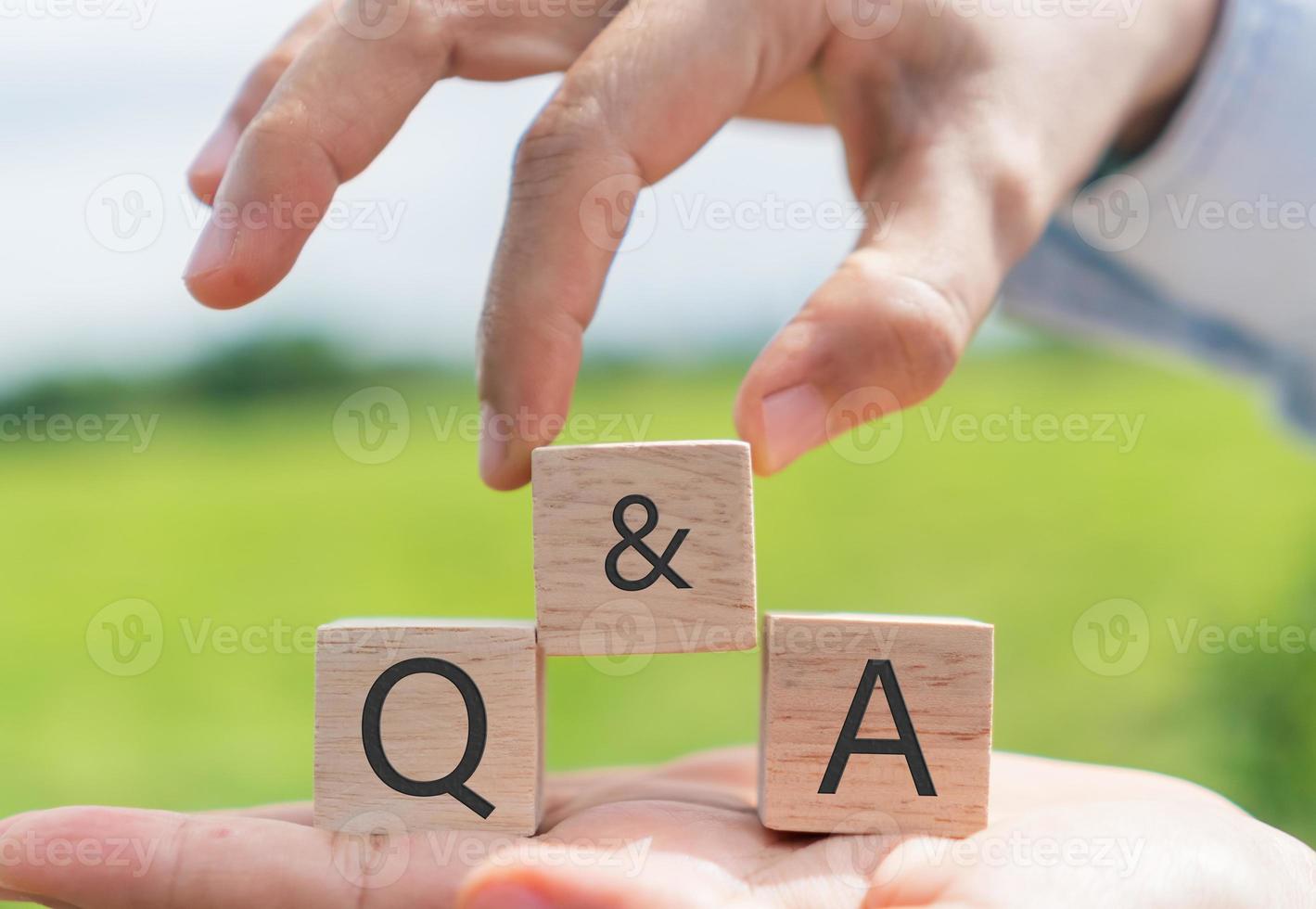 q en een alfabet op houten kubus in de hand houden met achtergrond foto