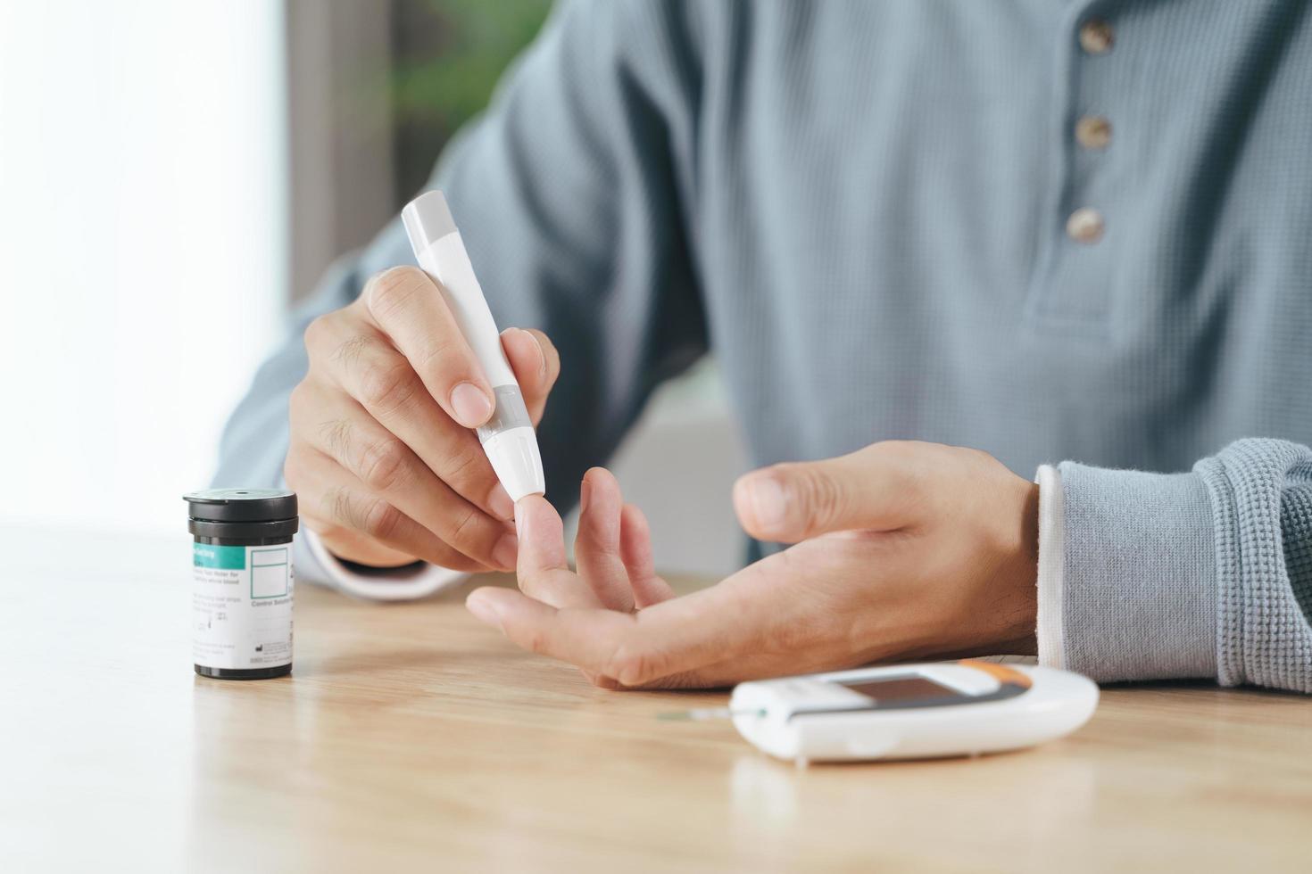 man die lancet op vinger gebruikt die bloedsuikerspiegel controleert met glucosemeter foto