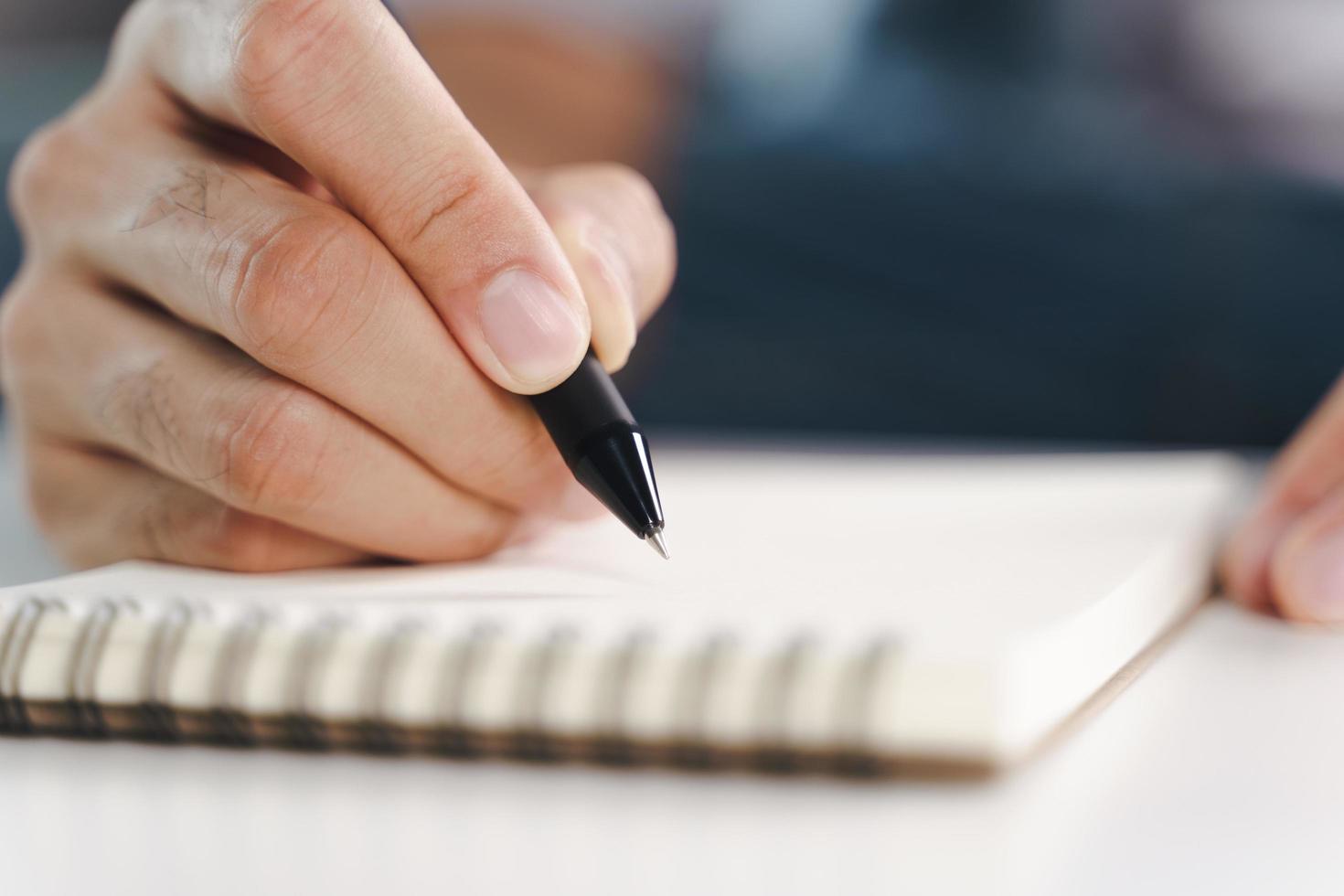 jonge man handen opschrijven op het notitieblok, notebook met pen foto