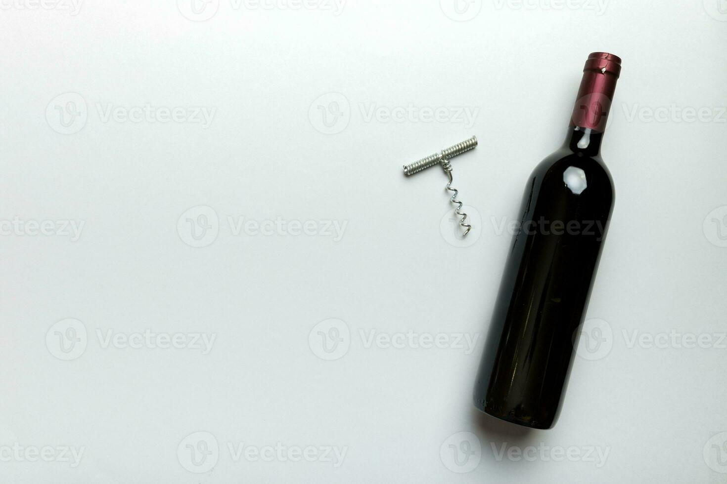 een fles van rood wijn met kurketrekker Aan gekleurde tafel. vlak leggen, top visie wth kopiëren ruimte foto