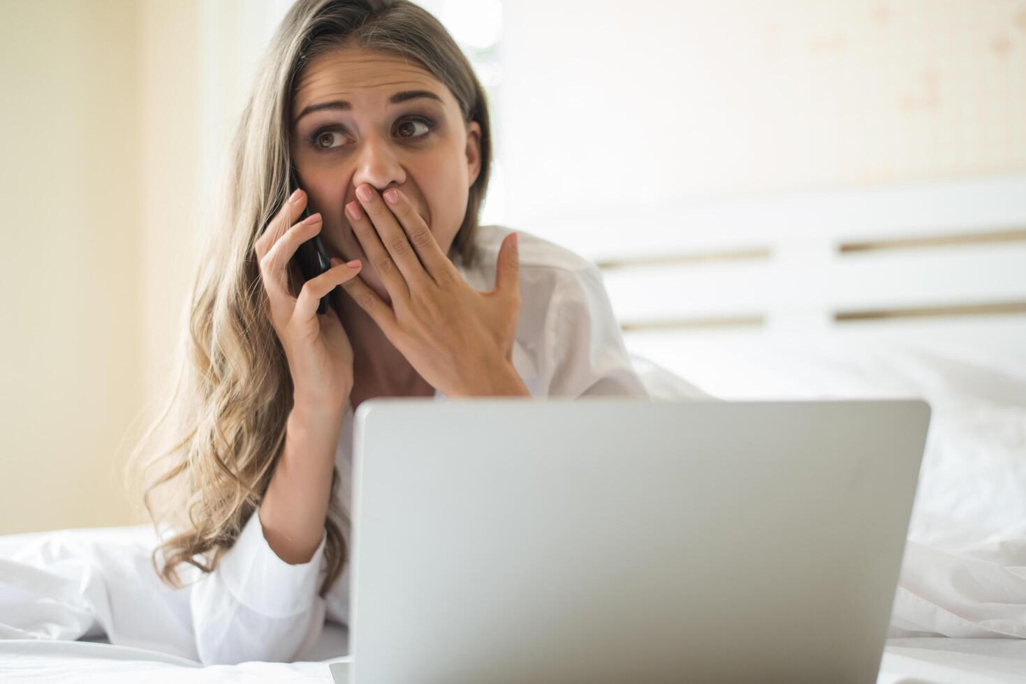 gelukkige mooie vrouw die aan laptop op het bed in het huis werkt foto