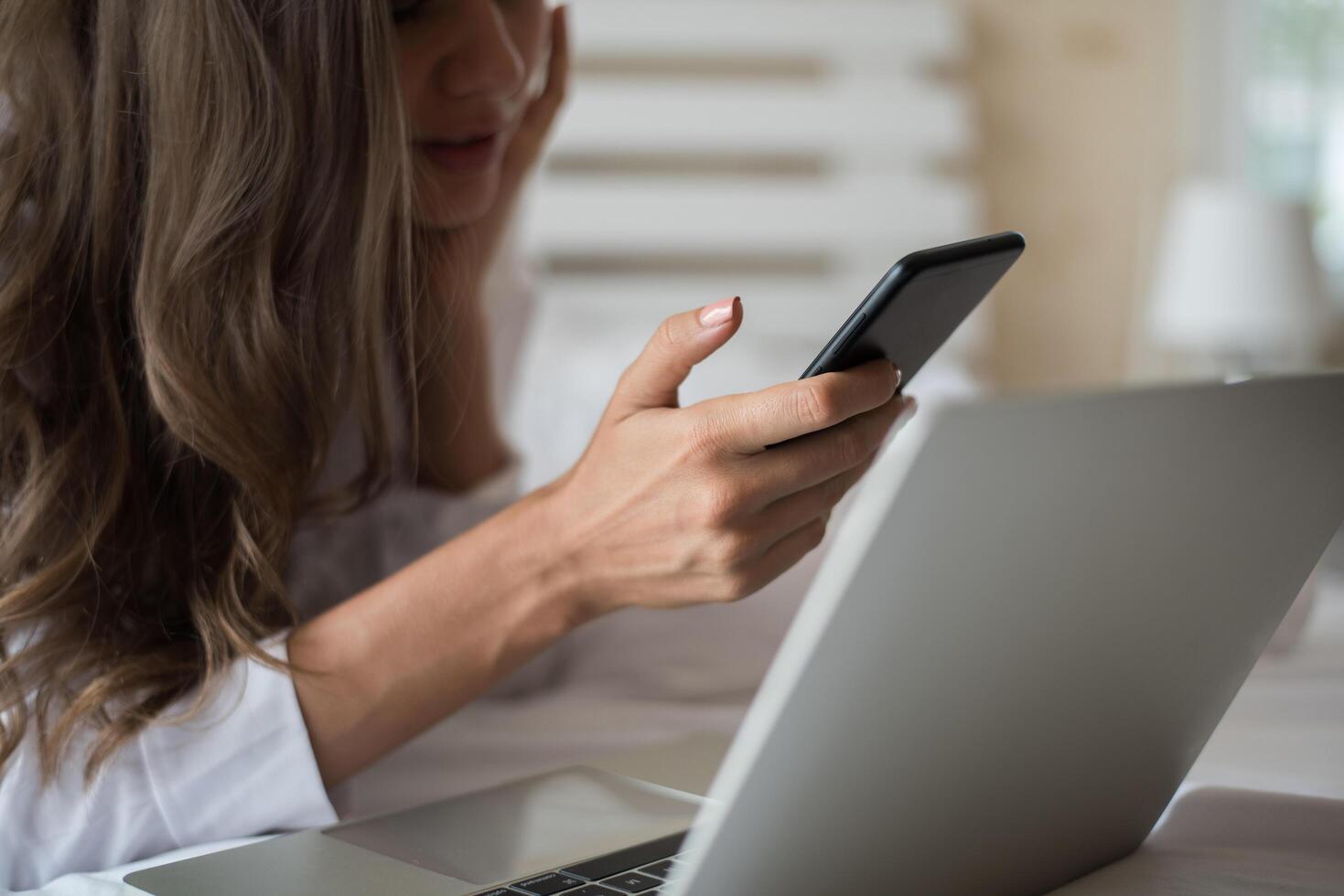 gelukkige mooie vrouw die aan laptop op het bed in het huis werkt foto