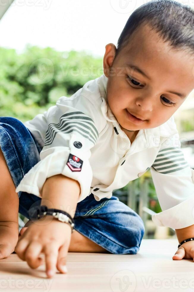 baby jongen Bij huis balkon. helder portret van gelukkig kind zittend Aan de tafel. weinig 1 jaar oud jongen gedurende de dag licht Bij huis balkon. foto