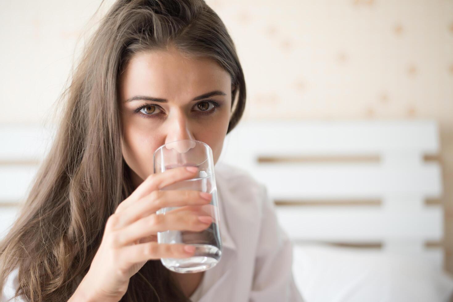 mooie vrouw die 's ochtends zoet water in bed drinkt foto