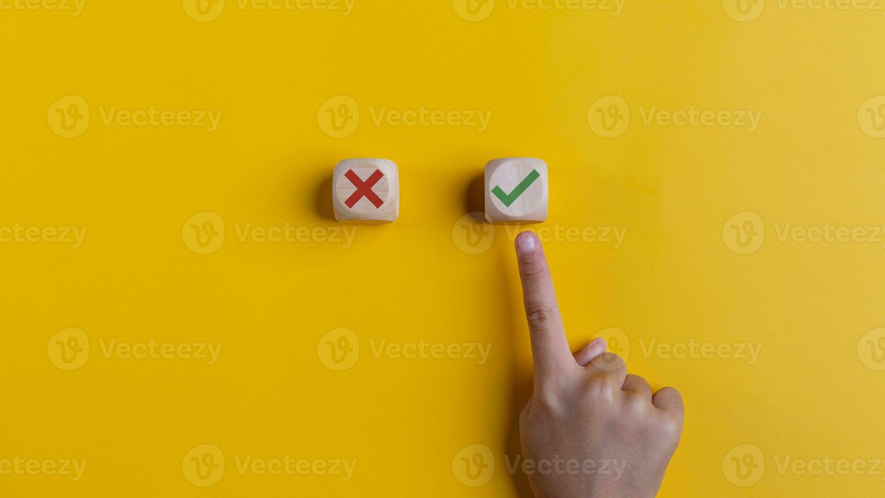 Rechtsaf en mis pictogrammen Aan houten kubussen met hand- kiezen de Rechtsaf icoon Aan geel achtergrond. goedkeuren, stemmen, of Rechtsaf besluit concept. foto