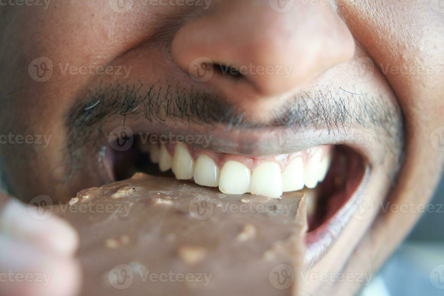 jonge man die donkere chocolade eet close-up foto