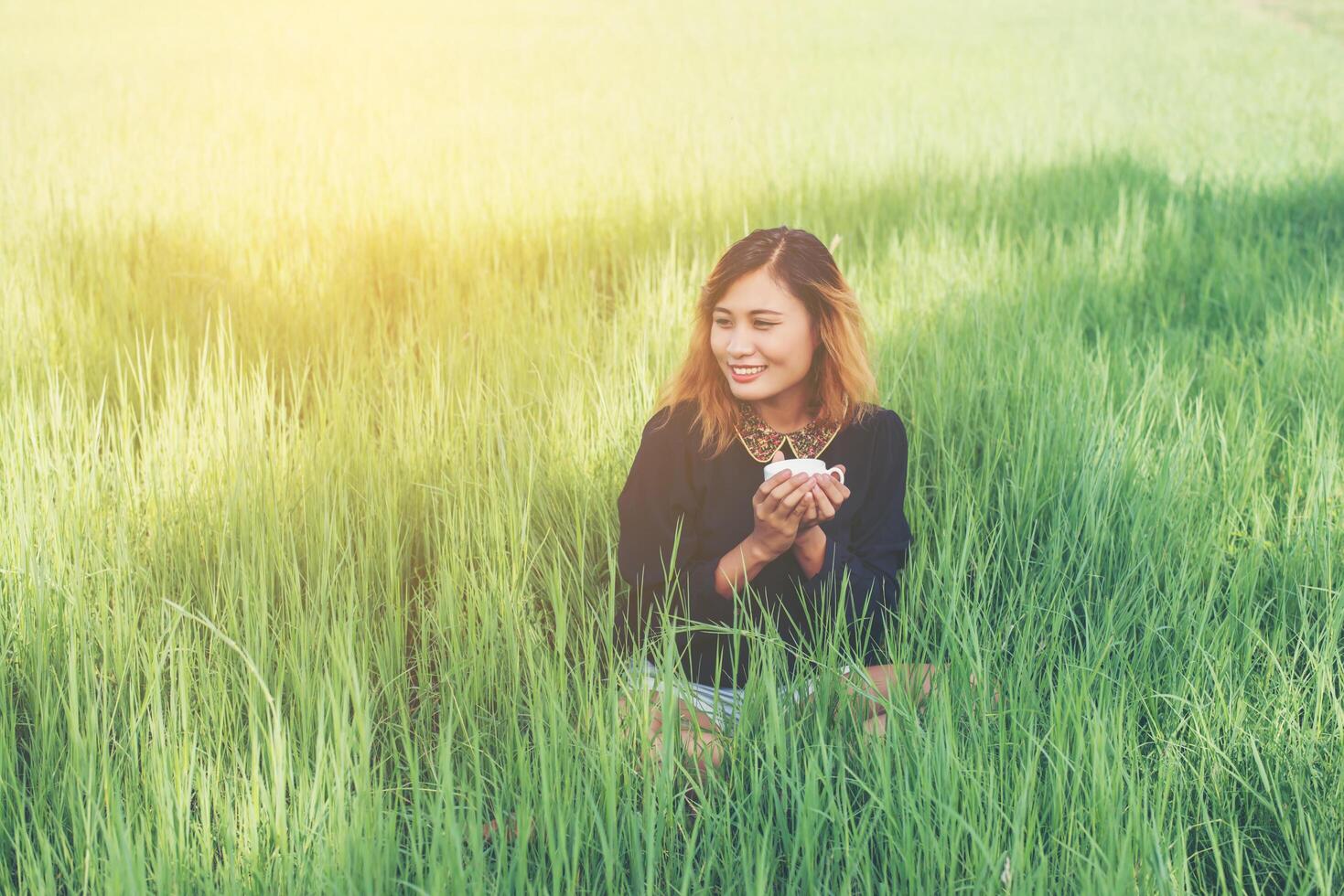 vrouw zittend op groen gras koffie drinken en genieten van de frisse lucht foto