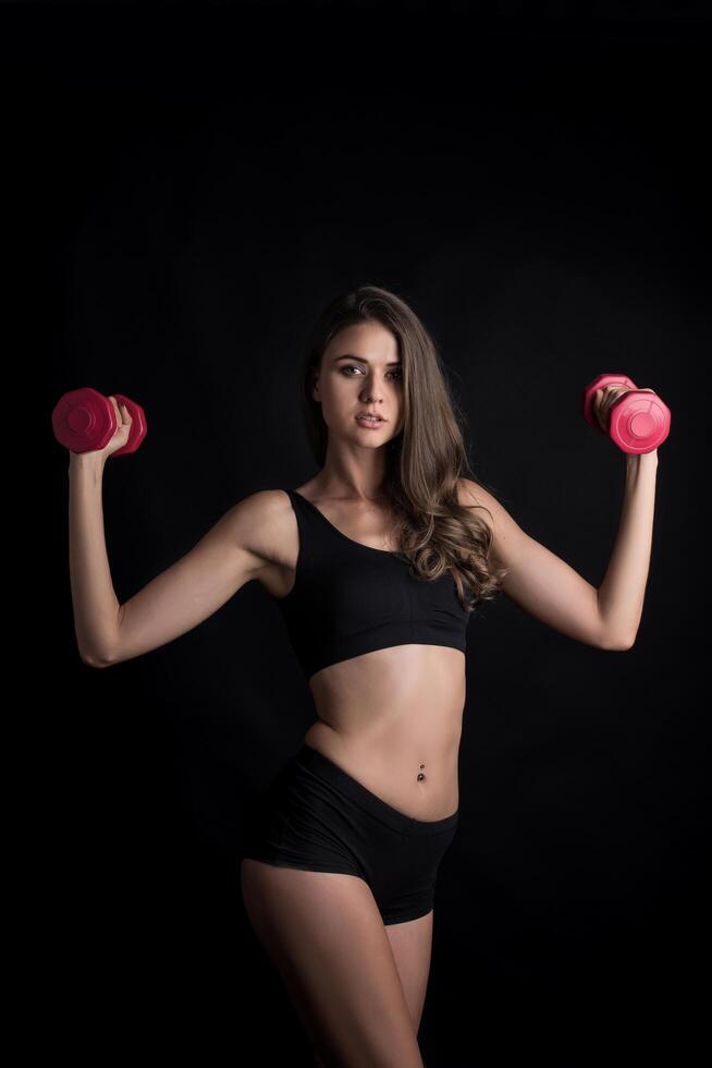 jonge mooie vrouw die fysieke oefeningen doet met halters foto