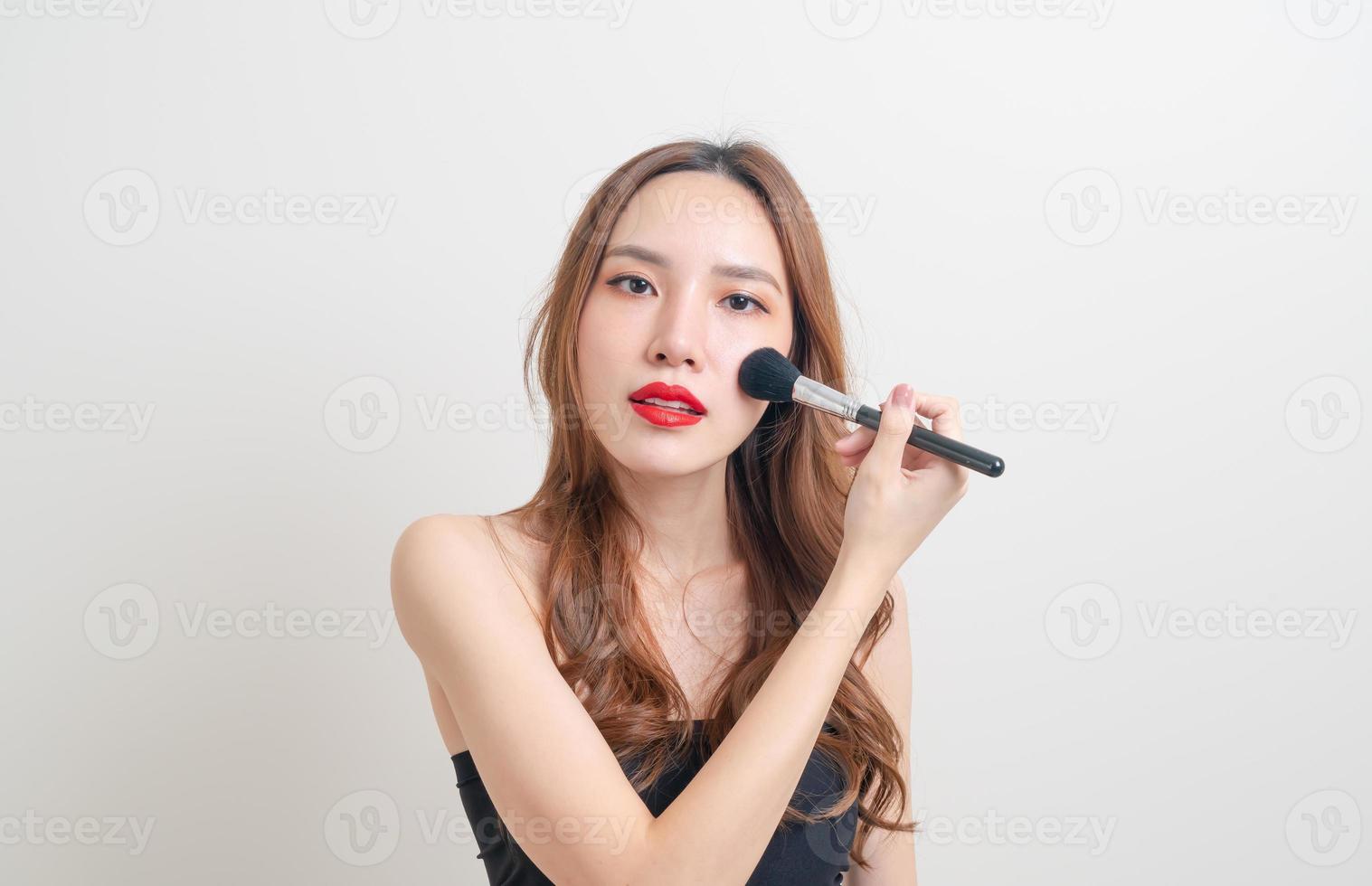 portret mooie Aziatische vrouw met make-up borstel op witte achtergrond foto