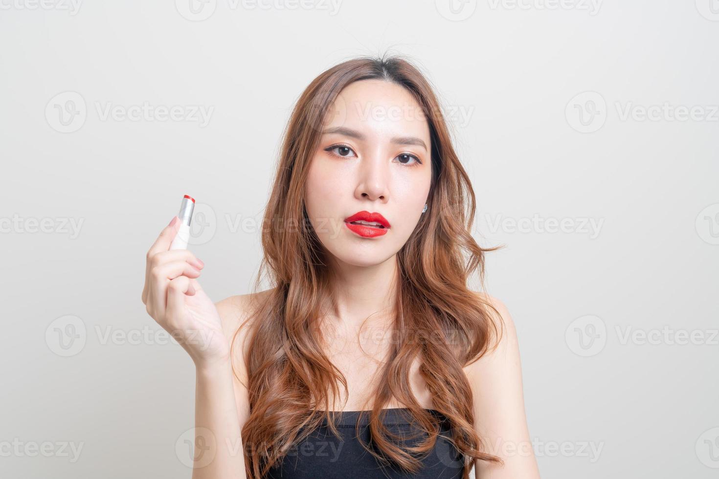 portret mooie aziatische vrouw die rode lippenstift op een witte achtergrond verzint en gebruikt foto