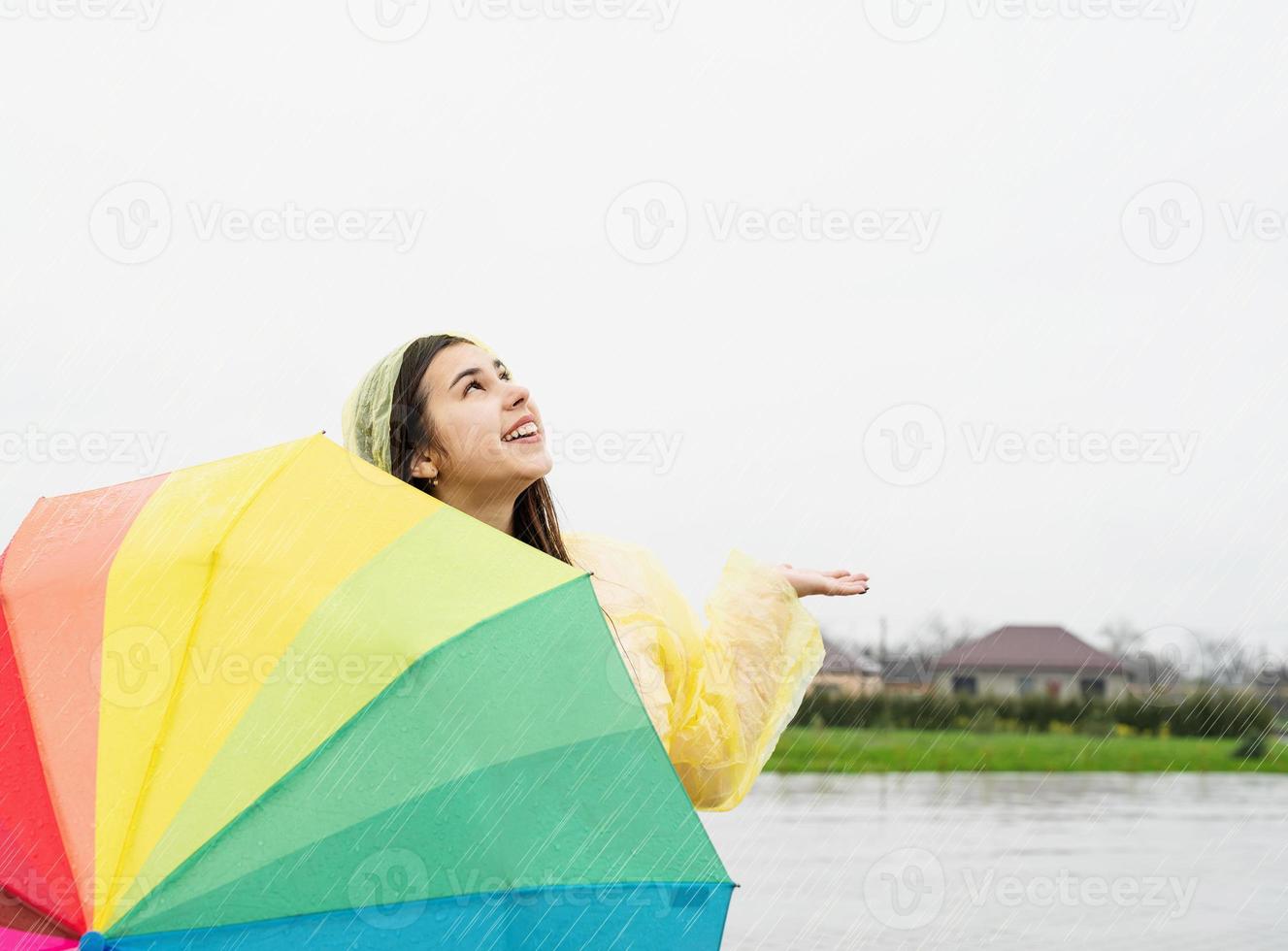 mooie donkerbruine vrouw die kleurrijke paraplu in de regen houdt foto