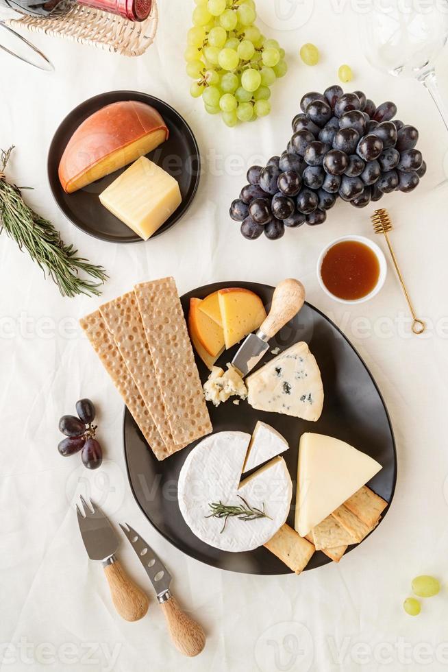 assortiment kaasplanken geserveerd met honing, druiven, brood en rozemarijn foto