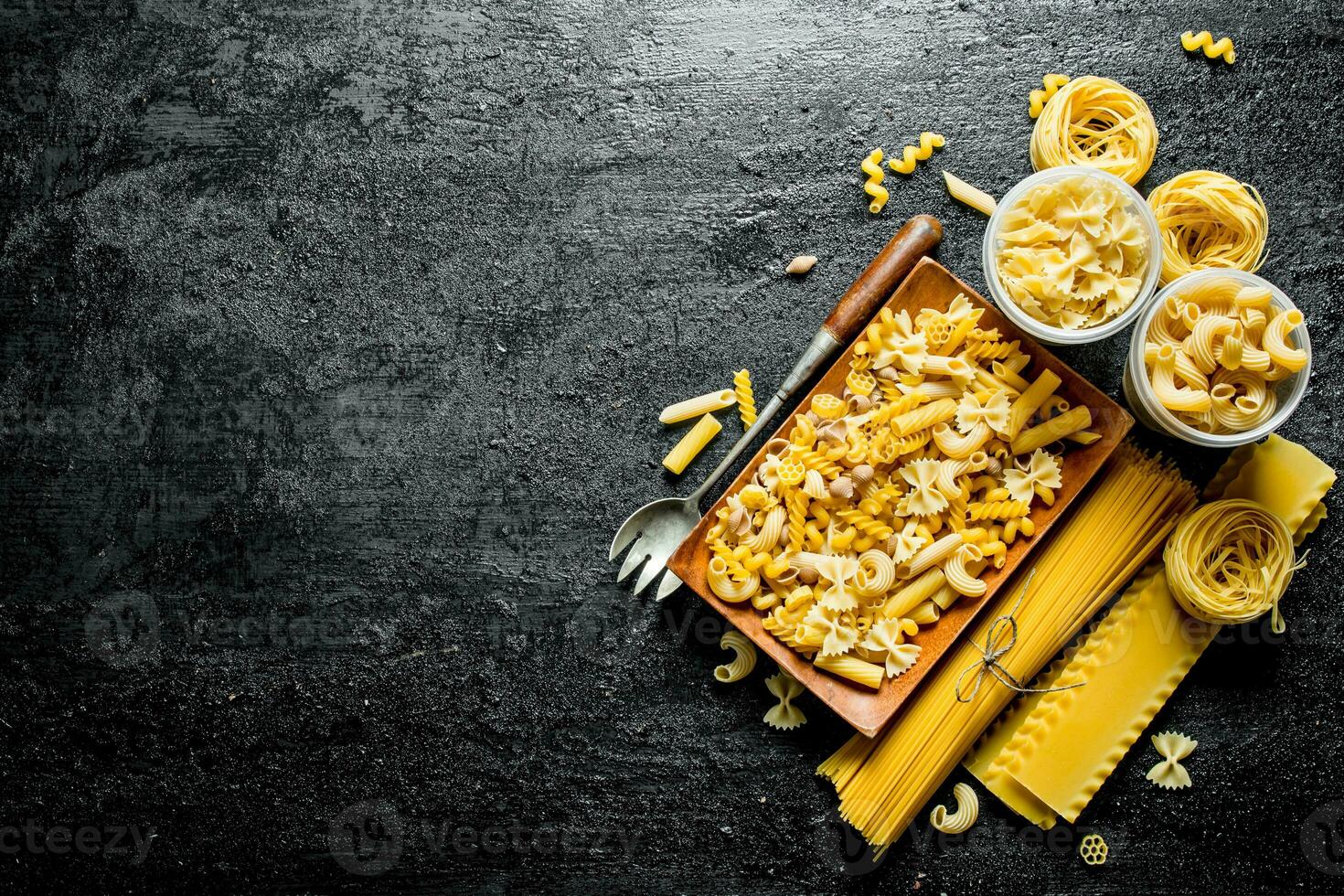 assortiment van verschillend types van droog pasta Aan een bord met pollepel. foto