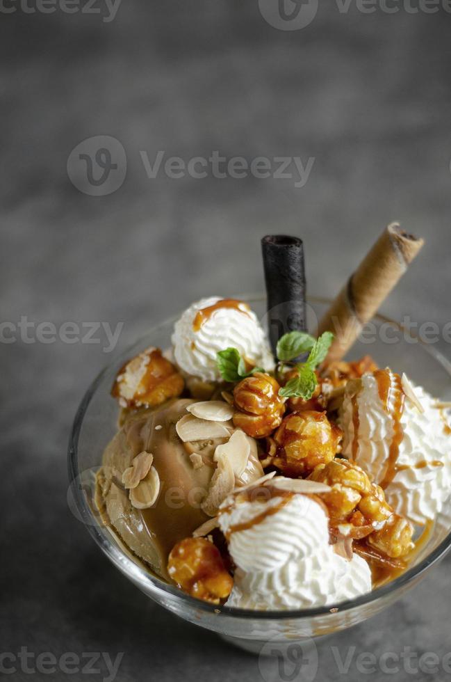 karamel- en amandelijs met gekarameliseerd popcornijscoupedessert in glazen kom foto