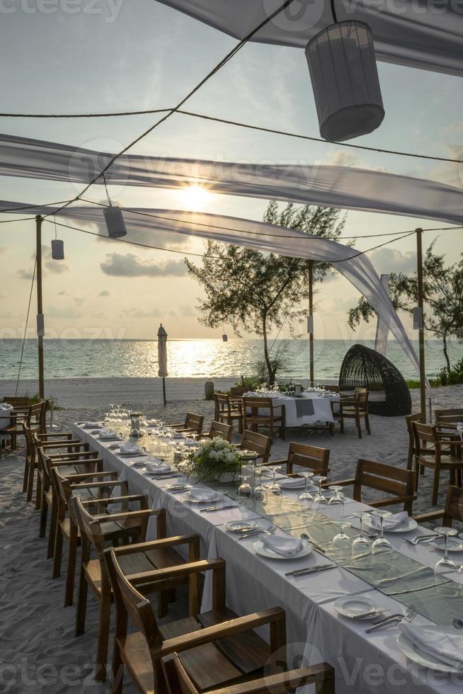 romantisch huwelijkstafelontwerp bij zonsondergang buiten op tropisch Aziatisch strand in Bali Indonesië foto