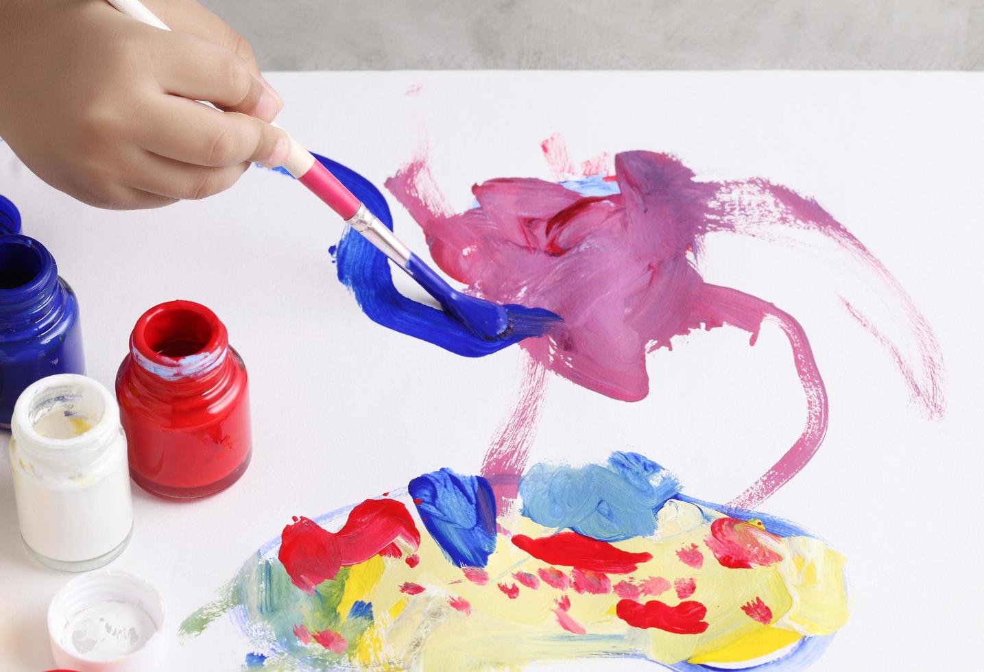 Aziatische jongen gebruikt penseel en aquarel op papier foto