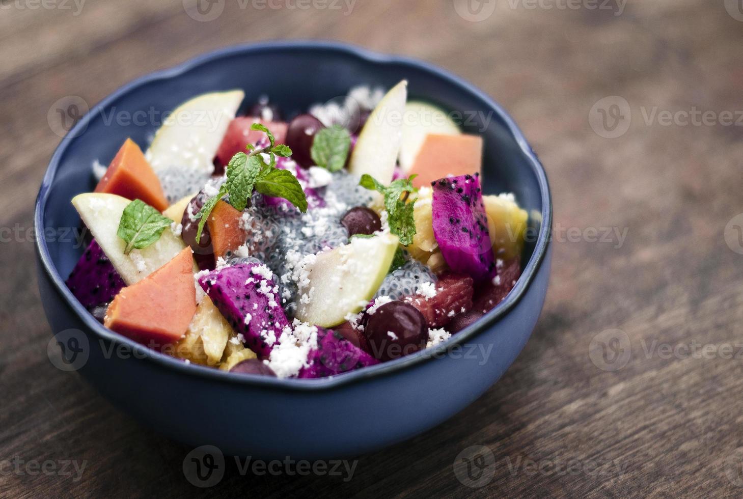 exotische gemengde tropische Aziatische fruitsalade met basilicumzaden en kokosnoot in kom buiten foto