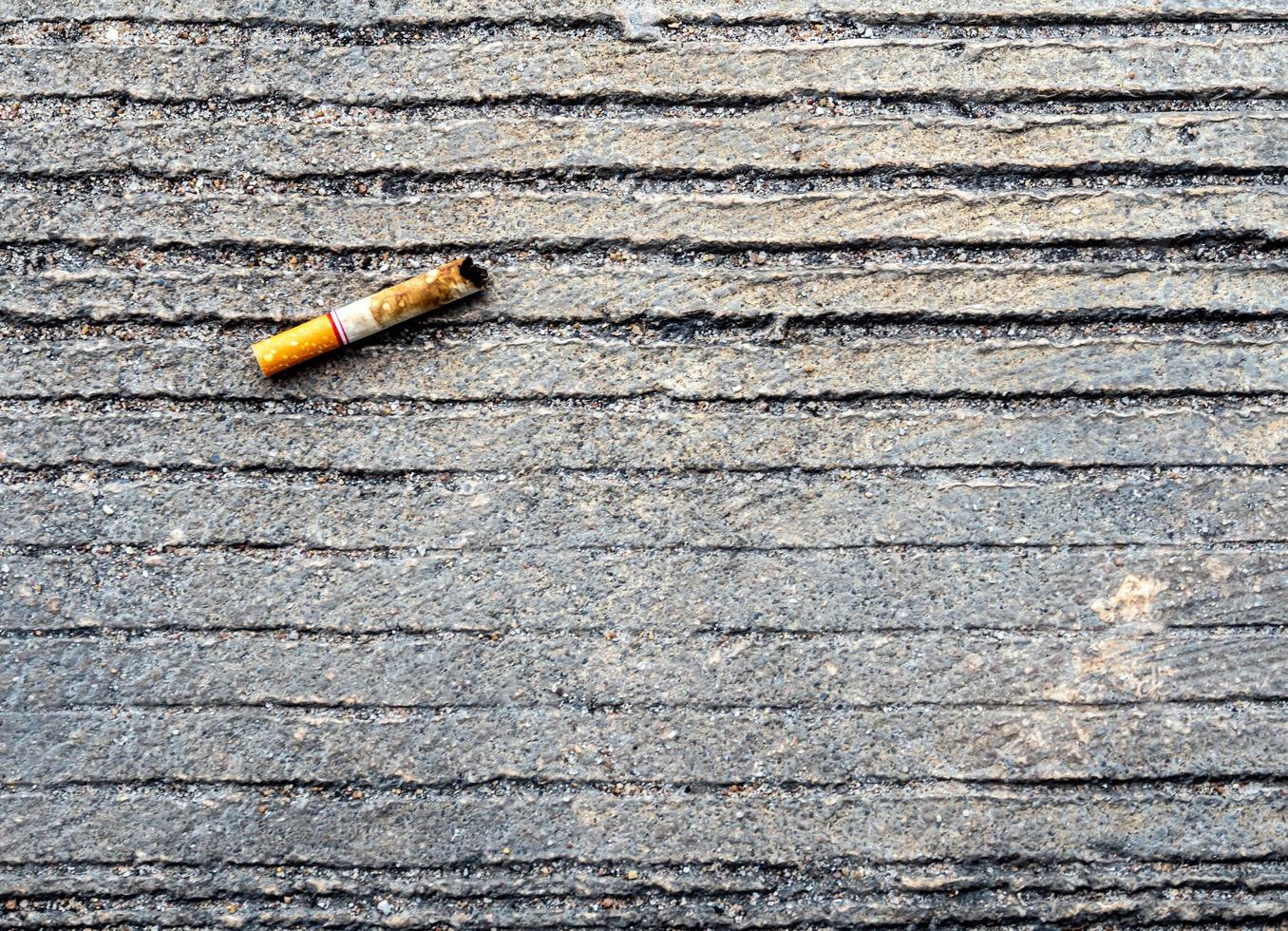 de sigarettenpeuk neergelaten op de betonnen vloer foto