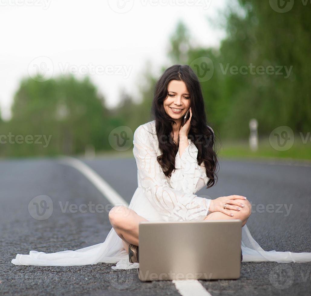 jonge vrouw die laptop op landweg gebruikt foto